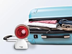 Maleta vintage azul claro llena de ropa doblada. Un dispositivo circular rojo con cable, posiblemente una plancha de viaje, se encuentra al lado de la maleta